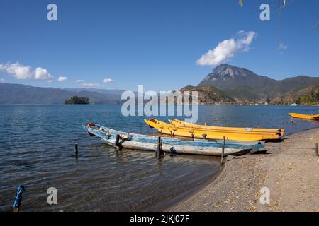 A bunch of boats on the shore of Lugu Lake under a bright sky in Yunnan, China Stock Photo