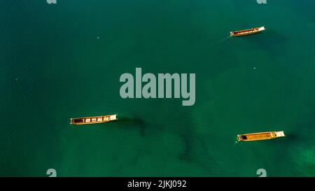 A top view of three wooden boats on the green Lugu Lake in Yunnan, China Stock Photo
