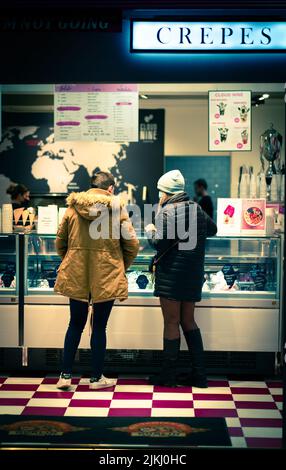 A back shot of a couple standing in a restaurant choosing what to order at night time in Dublin, Ireland Stock Photo