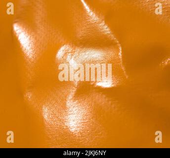 A closeup shot of an orange leather surface as a background Stock Photo