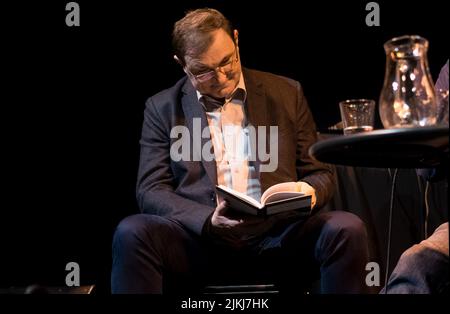 Old man reading a book during a public discussion indoors Stock Photo