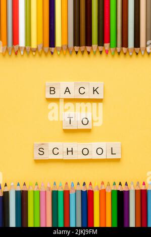 Back to class. Coloured pencils and letters BACK TO SCHOOL on yellow background. Copy space. Stock Photo