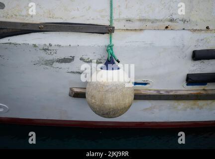 A sea buoy hanging from a green rope near the wall Stock Photo