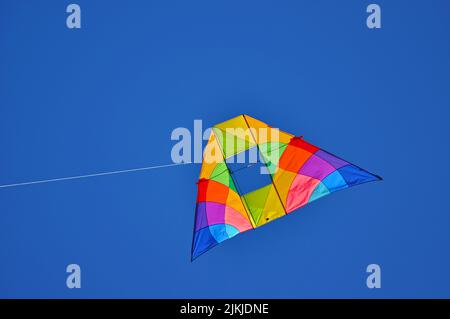 A colorful kite flying in the blue clear sky Stock Photo
