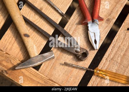 A top view of various metallic rusty tools on a wooden table in a workshop Stock Photo