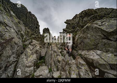 A low-angle shot of a male tourist with a backpack hiking in the High Tatras mountains Stock Photo
