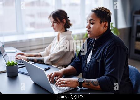 Portrait of two modern women using laptops while working in office together Stock Photo