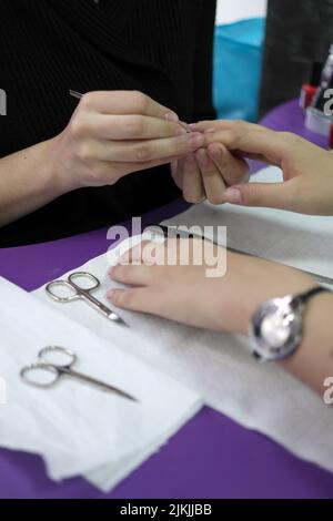 the  professional manicurist does a service for painting nails. The nail polish gel coating is as close to the cuticle as possible. Stock Photo