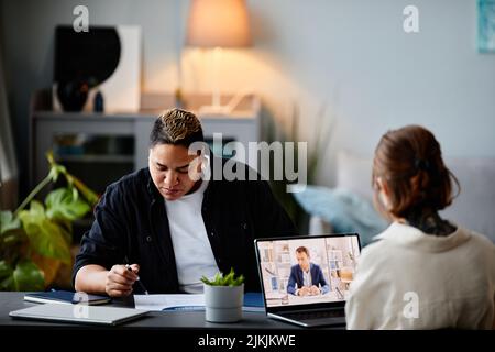 Portrait of two modern businsswomen working at table together with focus on online meeting computer screen, copy space Stock Photo