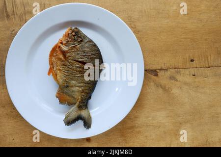 pomfret on white plate with wooden table Stock Photo