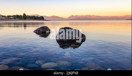 A scenic shot of two rocks submerged partly in crystal clear water, with pebbles visible underwater Stock Photo