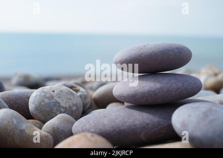 Smooth purple pebbles stacked on pebbly beach in Cornwall Stock Photo