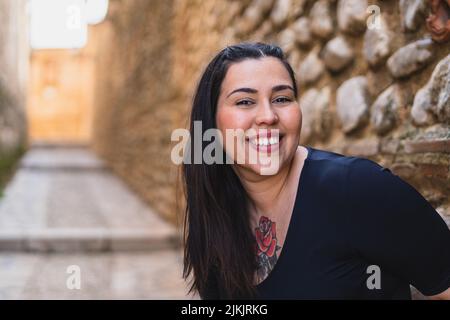 A beautiful smiling caucasian woman with tattoos posing on a stone wall background Stock Photo