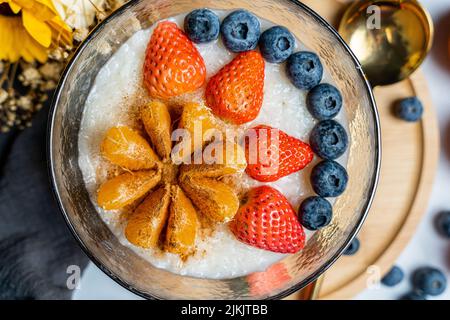A top view of rice porridge with tangerine, strawberry, blueberry Stock Photo