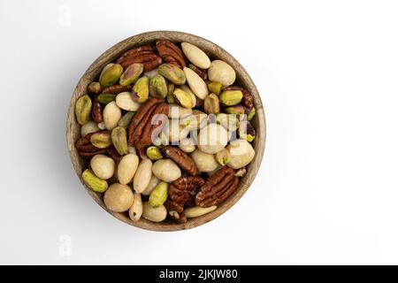 mixed nuts in wooden bowl isolated on white background, top view, peeled pistachio, macadamia, almonds, hazelnuts and pecan, healthy snack Stock Photo