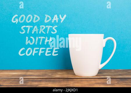 A white coffee cup on a blue background with 'GOOD DAY STARTS WITH COFFEE' writing Stock Photo