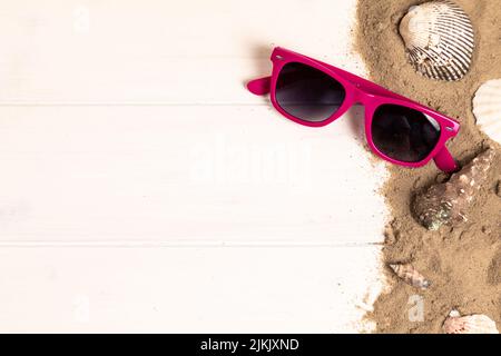 sunglasses with sand and shellfish on white wooden background Stock Photo