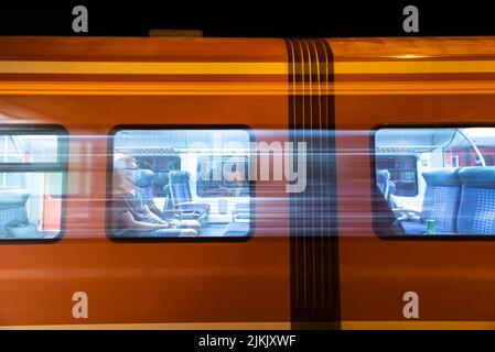 A guy in a medical mask on a modern orange train passing by Stock Photo