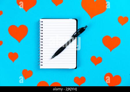 paper with pen on a blue background with red hearts Stock Photo