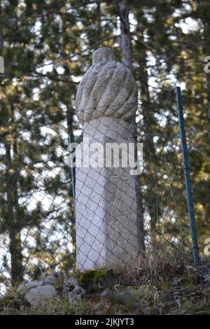 A vertical shot of a stone monument behind a mesh metal fence outdoors Stock Photo