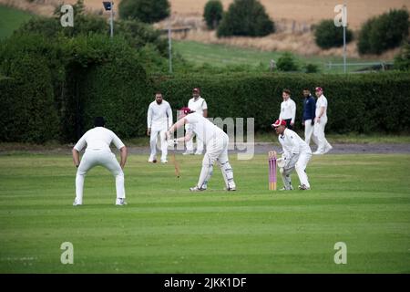 Cricket Batsman, Wicket keeper, fielders and spectators at a local village cricket match in Kirkheaton, Huddersfield, Yorkshire, U.K. Stock Photo