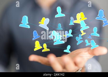 A social network connecting people icon floating in the palm of a man in white shirt Stock Photo
