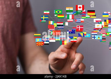 A businessman on a blurry background touching 3D rendering national flags icons Stock Photo