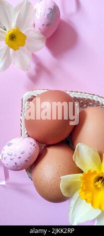 a  Top view shot of pink Easter egg decorations, chicken eggs in a bowl on a pink background. Stock Photo
