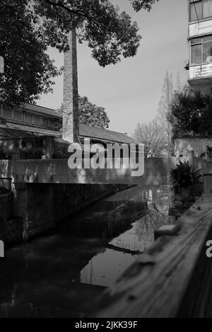 A grayscale shot of buildings and bridge over river in old village. Shanghai, China Stock Photo