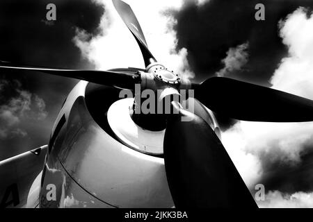 A low angle grayscale shot of an Aircraft motor with fan against a cloudy dark sky Stock Photo