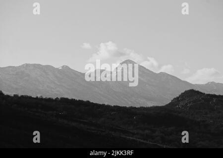 A grayscale shot of mountains under cloudy sky Stock Photo