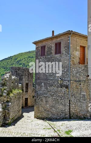 A vertical shot of a cobblestone street between old medieval stone buildings in the daytime. Stock Photo