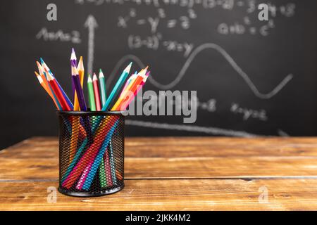 colored pencils on wooden background with chalkboard Stock Photo