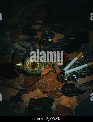 A vertical shot of cigarettes and a compass on a world map Stock Photo
