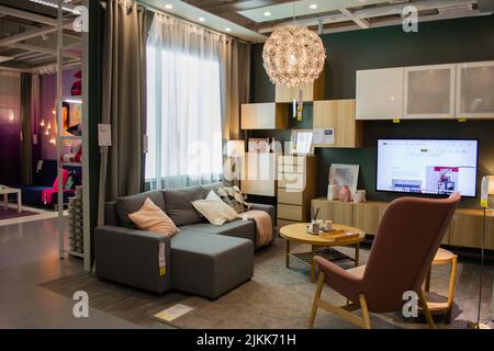 Moscow, Russia, September 2019: IKEA store interiors: bright living room, in natural colors, wooden furniture, TV and peeping from the left bright roo Stock Photo