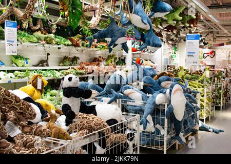 Moscow, Russia, February 2021: A bunch of soft toys on the shelves in an Ikea store: sharks, dinosaurs, pandas and snakes. Toys on shelves, on the cei Stock Photo