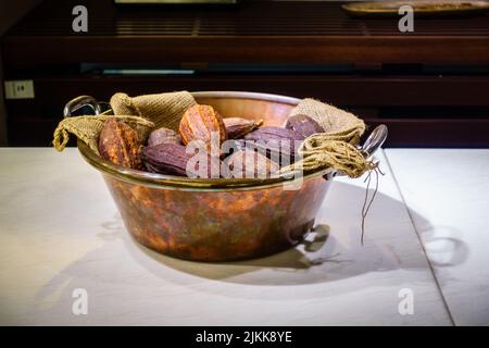 A closeup of cocoa beans in an old and rustic bowl with burlap cloth Stock Photo