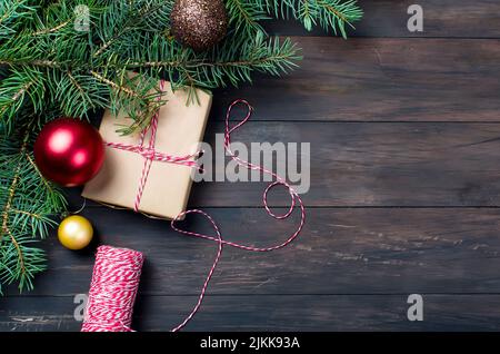 Christmas decorative box tied with a red ribbon , fir branches and christmas balls on the dark wooden background. Christmas card Holiday Concept Stock Photo
