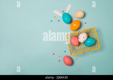 A top view shot of colorful easter eggs in a basket with a gray background and a copy space Stock Photo