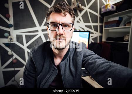 A Caucasian man with glasses taking a selfie in his office Stock Photo