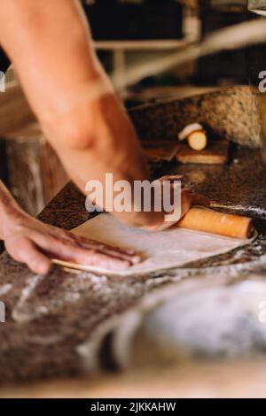 Male hands rolling out dough for pizza on a table Stock Photo