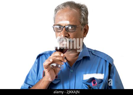 An Indian man in blue shirt drinking wine in white background Stock Photo