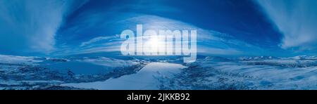 Aerial panoramic sunset over over Norwegian snowy winter mountains with frozen lake. Clear blue skies. Krutvatnet lake, Norway Stock Photo