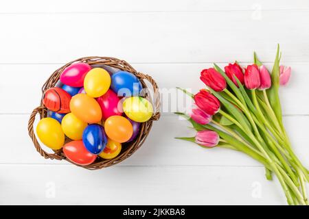 easter nest with colorful eggs and tulips on a white background Stock Photo