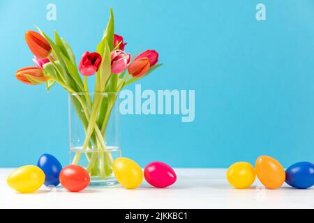 colorful tulips in a vase with colored easter eggs and copy space Stock Photo