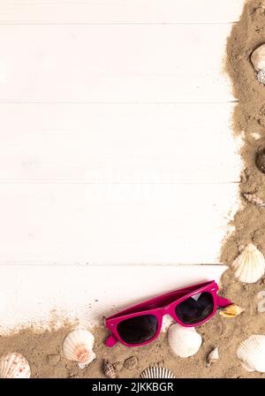 sunglasses with sand and shellfish on white wooden background Stock Photo