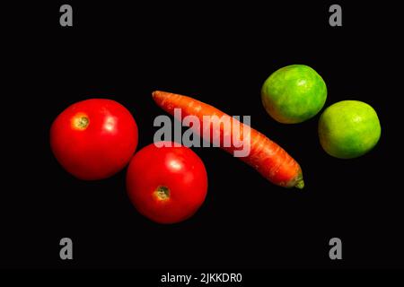 Tomatoes, carrot and lemons arranged on black isolated background Stock Photo