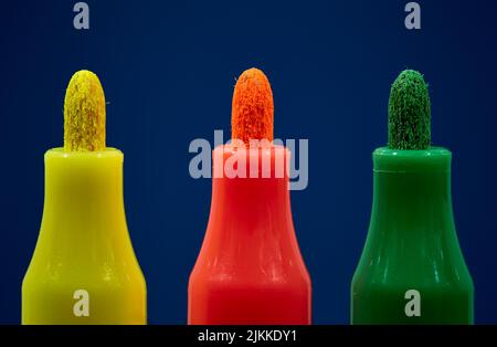 A closeup of green, red and yellow markers on a blue background Stock Photo