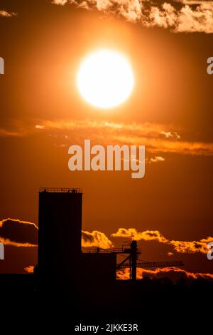 A vertical shot of a glowing orange sunset sky over modern building silhouettes Stock Photo