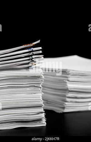 Stacks of papers with multicolored paper clips on a dark background Stock Photo